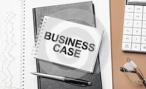 business case on notepad and various business papers on brown background. Brown glasses and magnifier with notepad