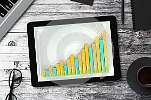 Business chart on the screen of the tablet with glasses, diary,