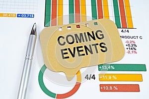 On the business charts is a pen and a sign with the inscription - Coming Events