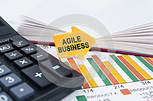 On the business charts there is a notepad, a pen and an arrow sticker with the inscription - Agile Business