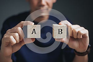 Business Choices For Difficult Situations, A or B, man holding two wooden cubes with A or B word on it, making decision