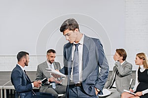 business coach looking at notebook in front of businesspeople at training