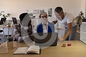 Business colleagues discussing over laptop in office