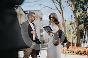 Business colleagues discussing project data on a tablet during an outdoor meeting in the city