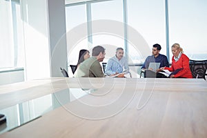 Business colleagues discussing while sitting against window at office