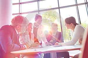 Business colleagues discussing while sitting at table in office lobby during meeting