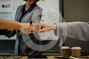 Business colleagues giving fist bump celebrating job success or work achievement.