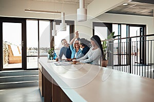 Business colleagues high fiving together during an office meetin