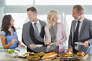 Business colleagues interacting while serving themselves at buffet lunch