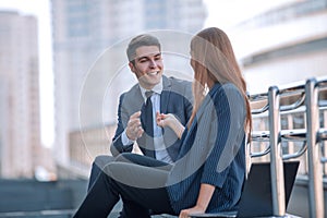 Business colleagues talking sitting on a bench near the office.