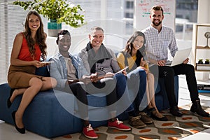 Business colleagues using electronic devices while sitting on sofa