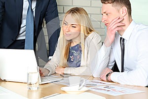 Business colleagues working together and analyzing financial figures on a laptop