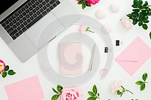 Business composition with laptop, envelope, pen and roses flowers on white background. Flat lay. Top view. Feminine composition