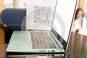 Business computer laptop on counter table with blur QR code in blur background.