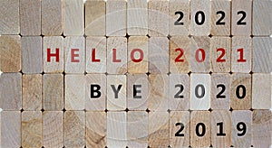 Business concept of 2021 new year. Wooden blocks with the words `bye 2020, hello 2021`. 2019, 2022 numbers. Beautiful wooden