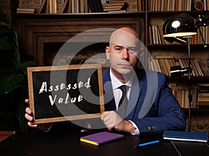 Business concept about Assessed Value with sign on chalkboard in hand photo