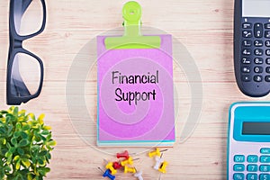 workplace with word FINANCIAL SUPPORT written on notepad