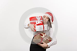 Business Concept - Beautiful young caucasian business woman with santa hat holding too much christmas gift boxes with