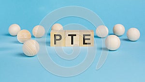 business concept. on the blue table wooden balls and wooden cubes with the inscription - PTE - Pearson Tests of English