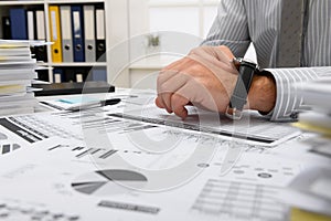 Business concept - businessman working in office and looks on wristwatch, table and workspace close view, checks financial reports