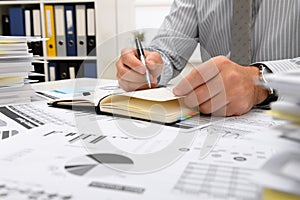 Business concept - businessman working in office, table and workspace close view, checks financial reports, writes and counts