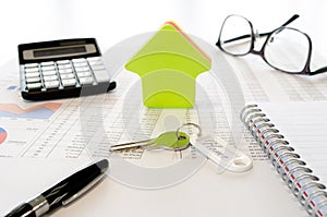 Business concept for buying or saving for a house  with , calculator, eyeglasses,  pen, keys, house shape and documents. Side view