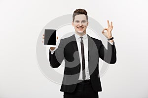 Business Concept: Cheerful businessman in smart suit with pc tablet showing ok. over grey background.