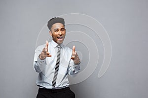 Business Concept - Cheerful happy young African American holding gun sign with fingers pointing to other.