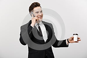 Business Concept: Close-up confident young handsome businessman talking on cell phone and drinking coffee over white