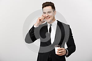 Business Concept: Close-up confident young handsome businessman talking on cell phone and drinking coffee over white