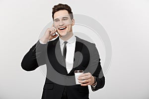 Business Concept: Close-up confident young handsome businessman talking on cell phone and drinking coffee over white