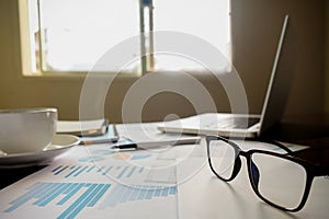 Business concept with copy space. Office desk table with pen focus and analysis chart, computer, notebook, cup of coffee on desk.