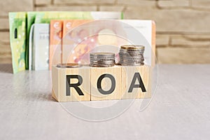 business concept. cubes with the inscription - ROA. euro and monet on grey table