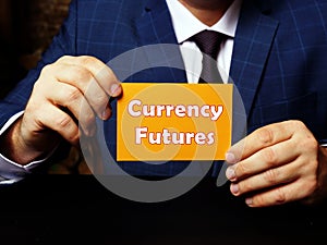 Business concept about Currency Futures with sign on orange business card in hand