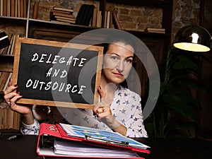 Business concept about DELEGATE AND OUTSOURCE with sign on the board