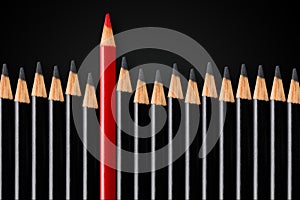 Business concept of disruption, leadership or think different; red pencil in front of row of black pencils standing out