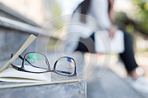 Business concept Eyeglasses for vision, lie with a notepad and a pencil, on the rung. Against the backdrop of a business woman