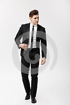 Business Concept: Full length portrait picture of a elegant business man in smart suit walking on white background.