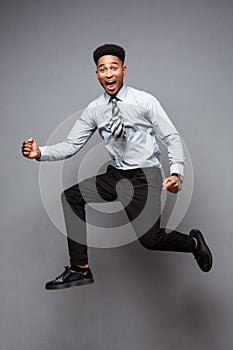 Business Concept - Full length portrait of successful african american businessman happy jumping in the office.