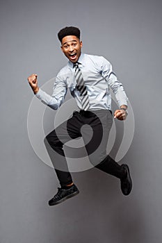 Business Concept - Full length portrait of successful african american businessman happy jumping in the office.