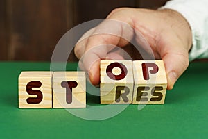 On a green surface, a man puts cubes with the inscription - STOP, STRES photo