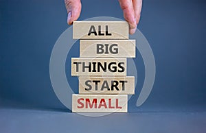 Business concept growth success process. Wood blocks on grey background, copy space. Businessman hand. Words `all big things star