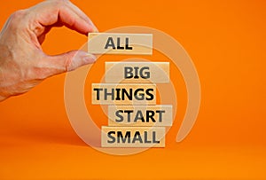 Business concept growth success process. Wood blocks on orange background, copy space. Businessman hand. Words `all big things