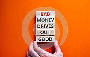 Business concept growth success process. Wood blocks on orange background, copy space. Businessman hand. Words `bad money drives