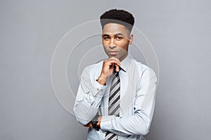 Business Concept - Happy confident professional african american businessman posing over grey background.