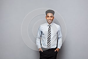 Business Concept - Happy confident professional african american businessman posing over grey background.