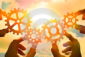Business concept idea. four hands of businessmen collect a puzzle from gears. Cooperation, teamwork, strategy