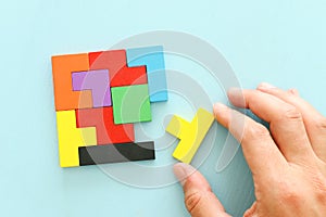 Business concept image of a colorful square tangram puzzle, over wooden table