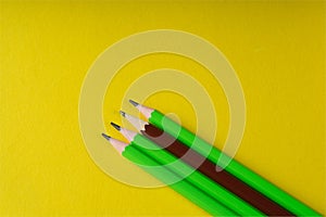 Business concept - lot of same pencils and one different pencil on yellow paper background. It`s symbol of leadership, teamwork.