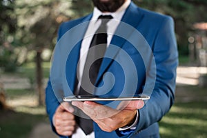 Business concept with man holding mobile phone with touch screen. Businessman holds lap top in his hand. Businessman in